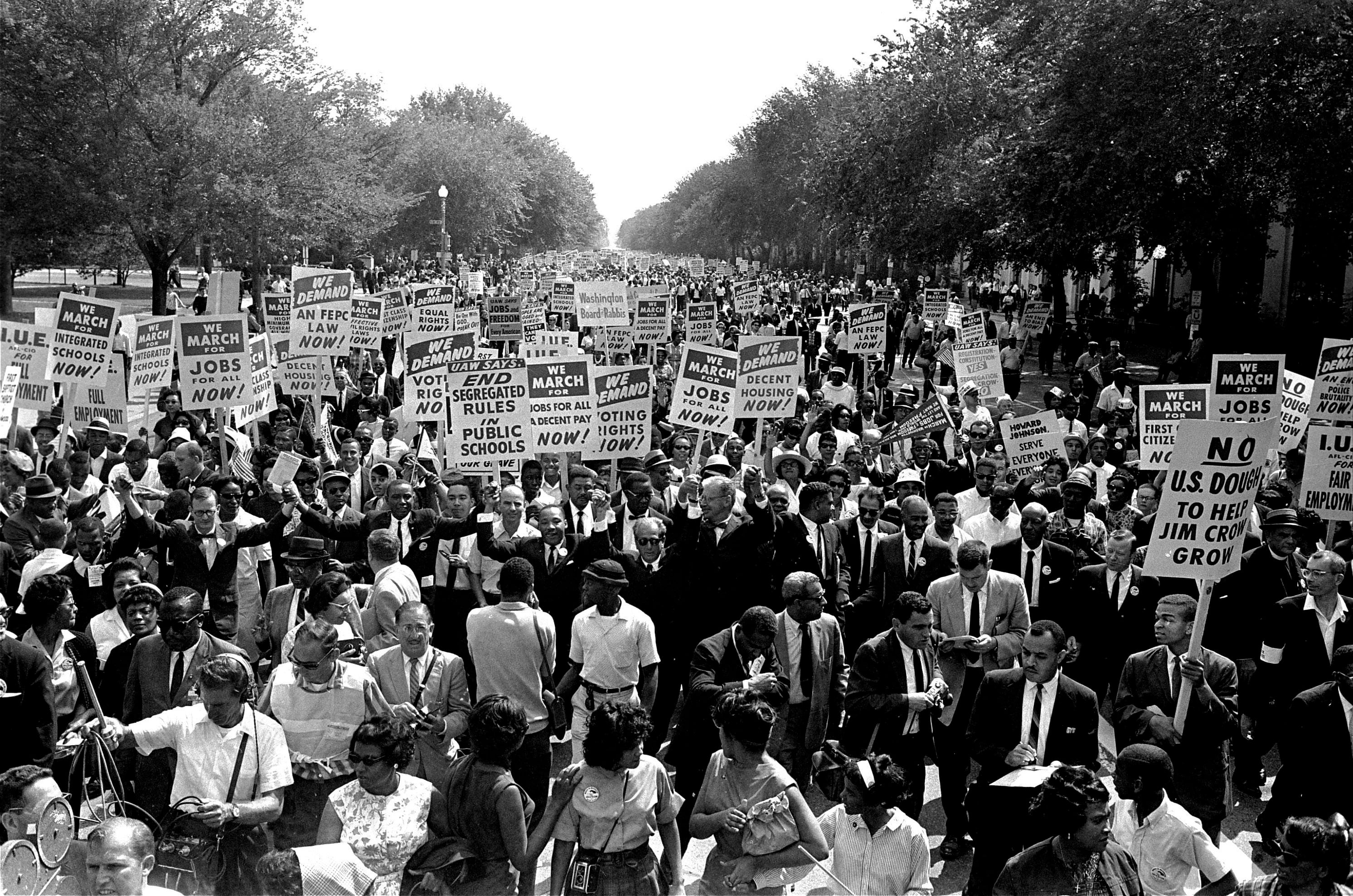 FILE - In this Aug. 28, 1963, file photo Dr. Martin Luther King Jr., center left with arms raised, marches along Constitution Avenue with other civil rights protestors carrying placards, from the Washington Monument to the Lincoln Memorial during the March on Washington. The annual celebration of the Martin Luther King Jr. holiday in his hometown in Atlanta is calling for renewed dedication to nonviolence following a turbulent year. The slain civil rights leader's daughter, the Rev. Bernice King, said in an online church service Monday, Jan. 18, 2021, that physical violence and hateful speech are out of control in the aftermath of a divisive election followed by a deadly siege on the U.S. Capitol in Washington by supporters of President Donald Trump. (AP Photo, File)