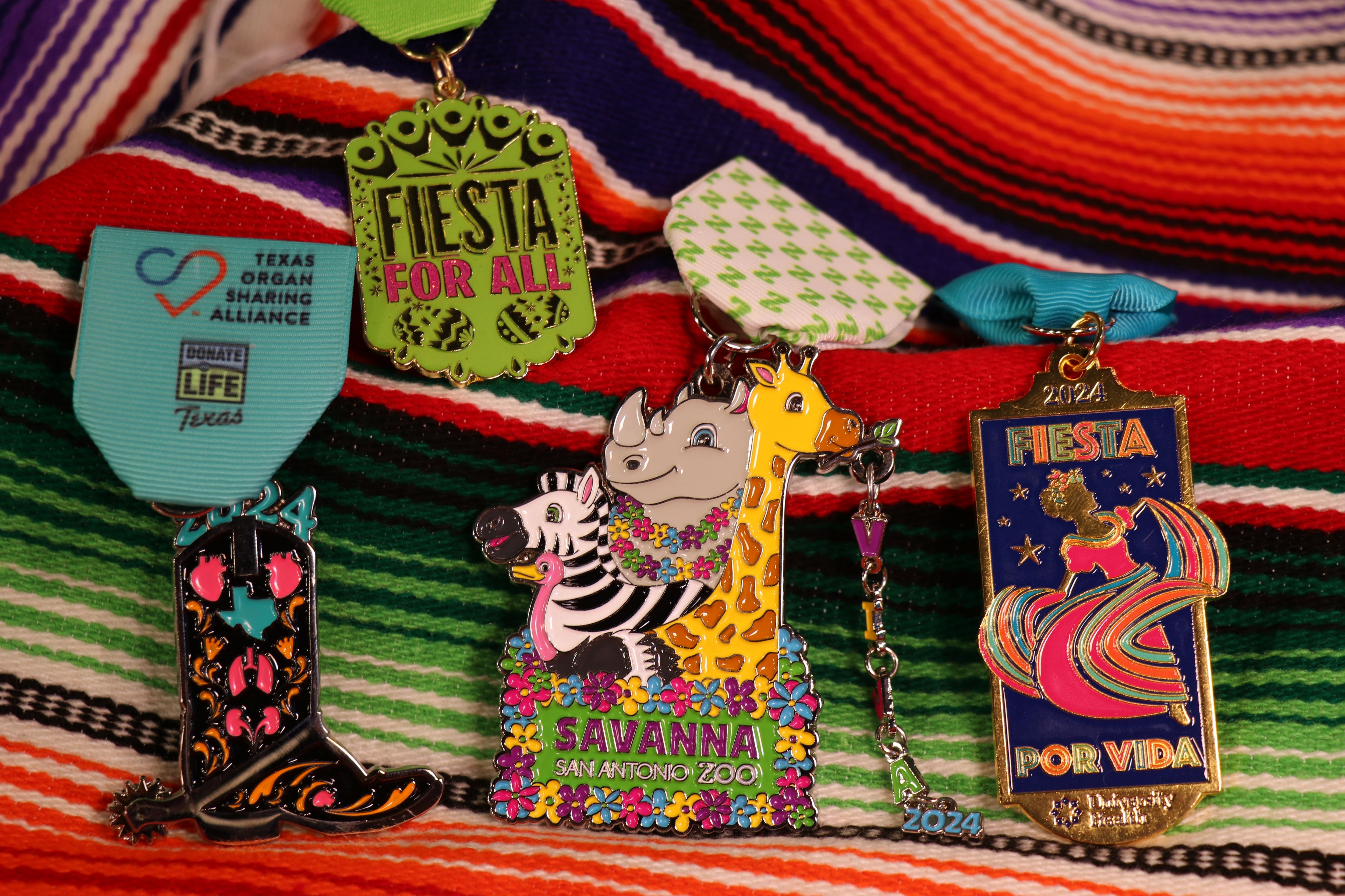 Pictured are the 2024 Fiesta medals for the Texas Organ Sharing Alliance, the Fiesta organization, the San Antonio Zoo and University Health.
